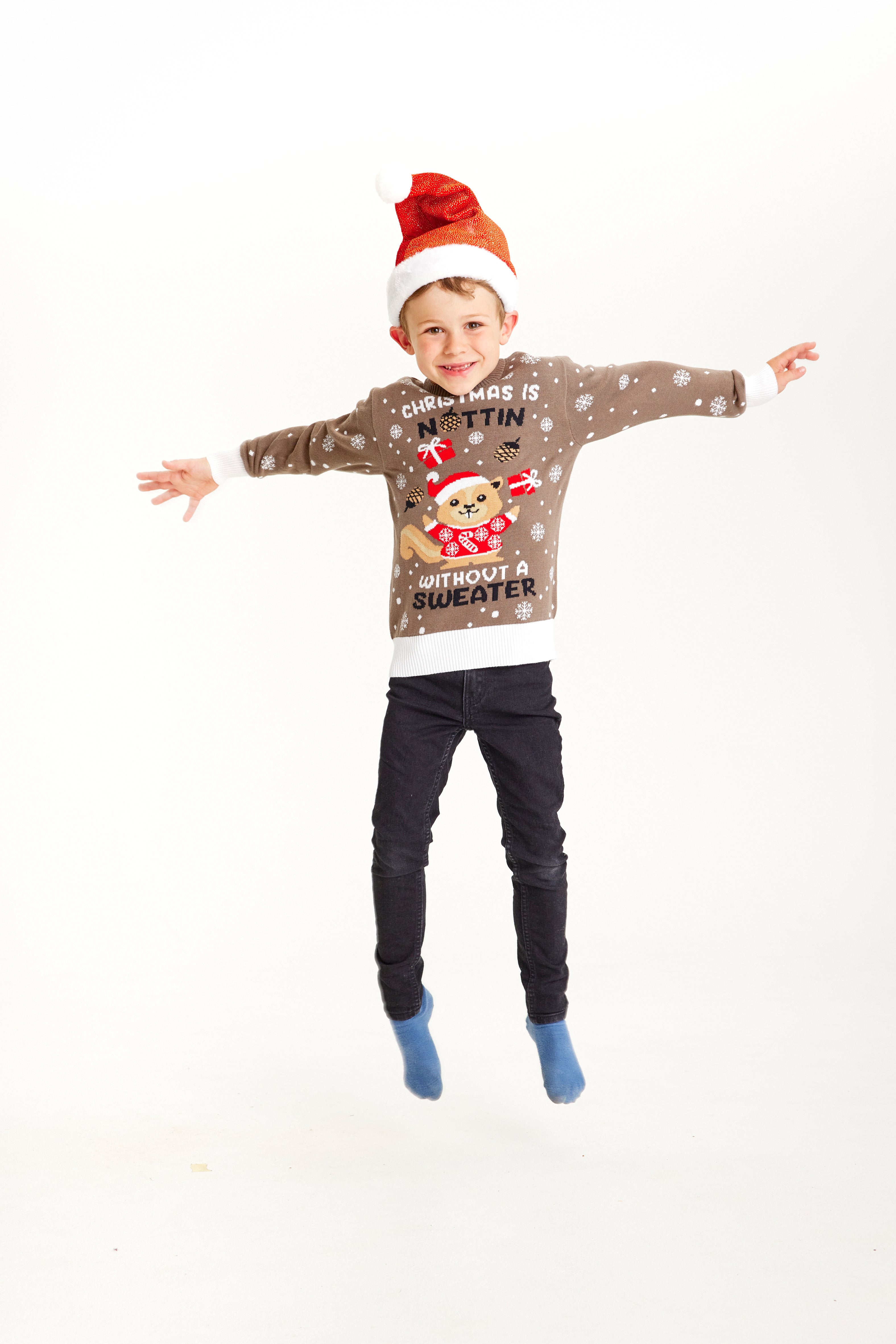 En hoppende dreng med en julesweater, hvor der står